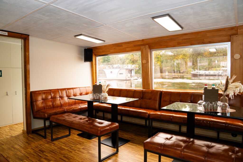 Eventschiff 2: Lounge-Ecke mit Ledersofas und großen Fenstern im Unterdeck